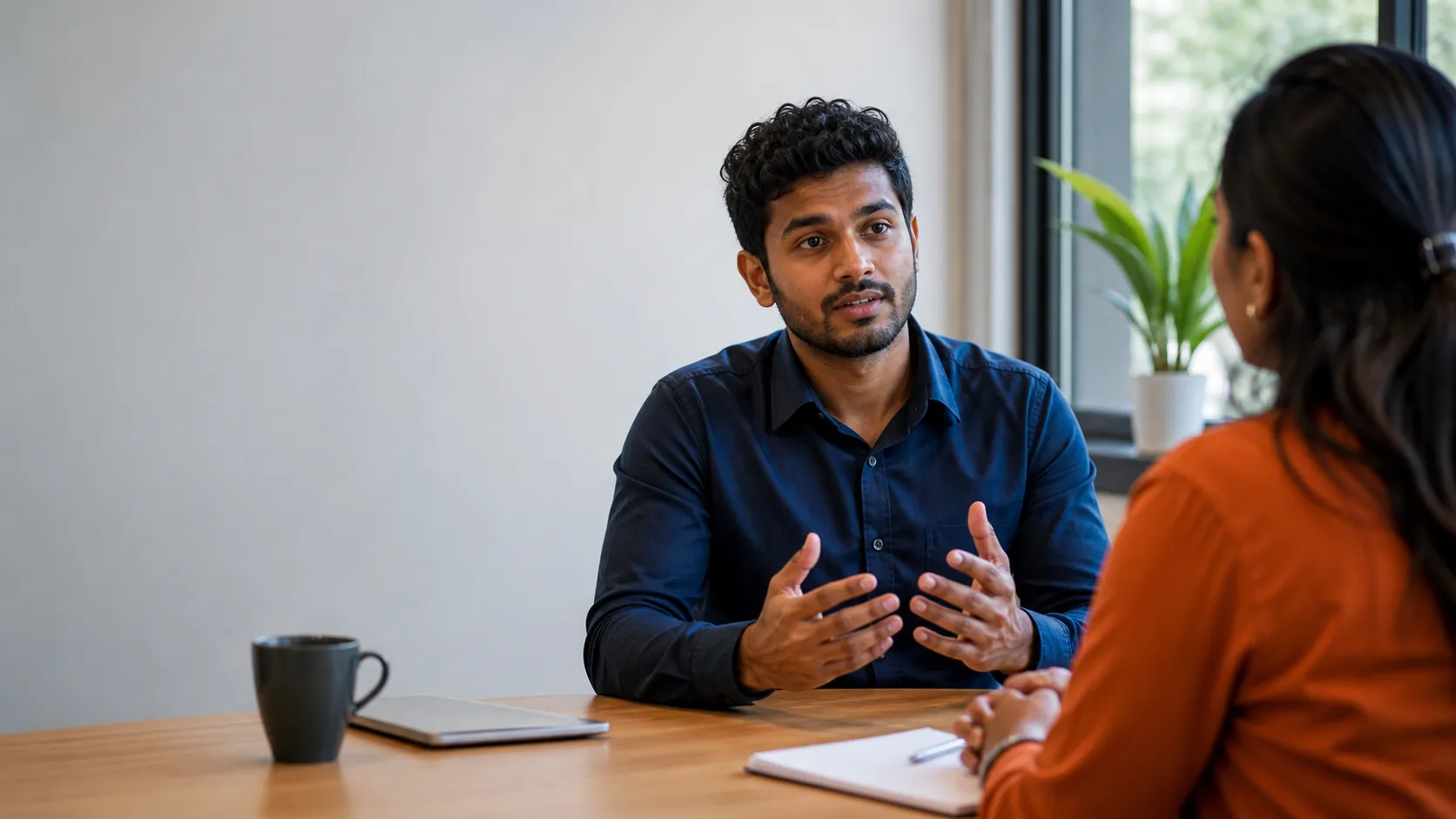 Sri Lankan-Australian job candidate practising an interview with a supportive mentor across a simple office table