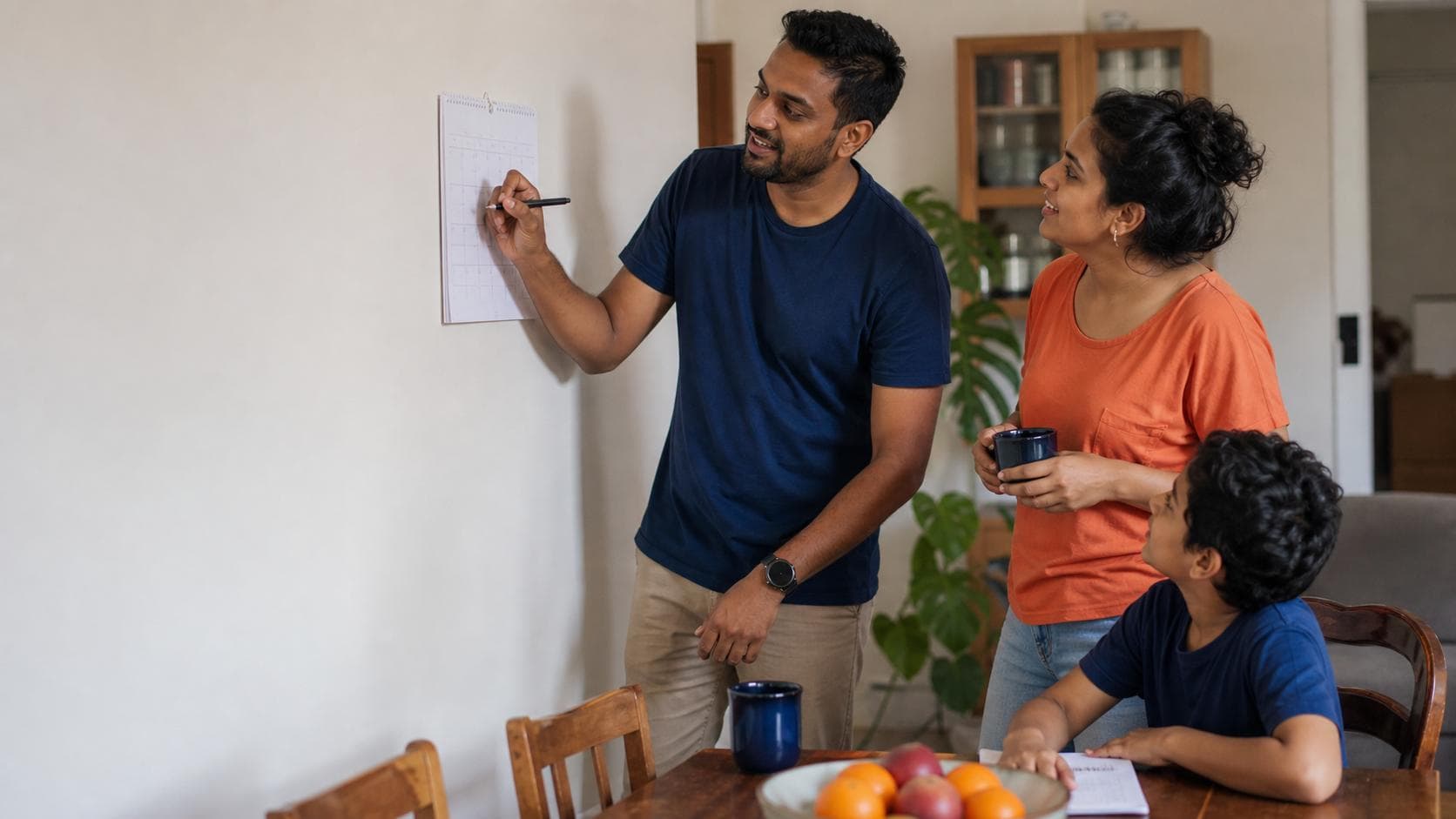 Sri Lankan-Australian family discussing a weekend plan while marking an unreadable wall calendar at home